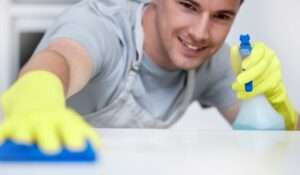 Master Of A Clean Home. Shot Of A Young Man Cleaning His Kitchen Counter