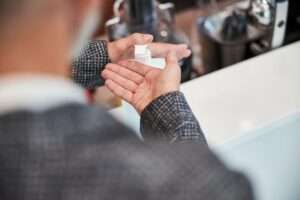 Senior Citizen Desinfecting His Hands With A Sanitizer
